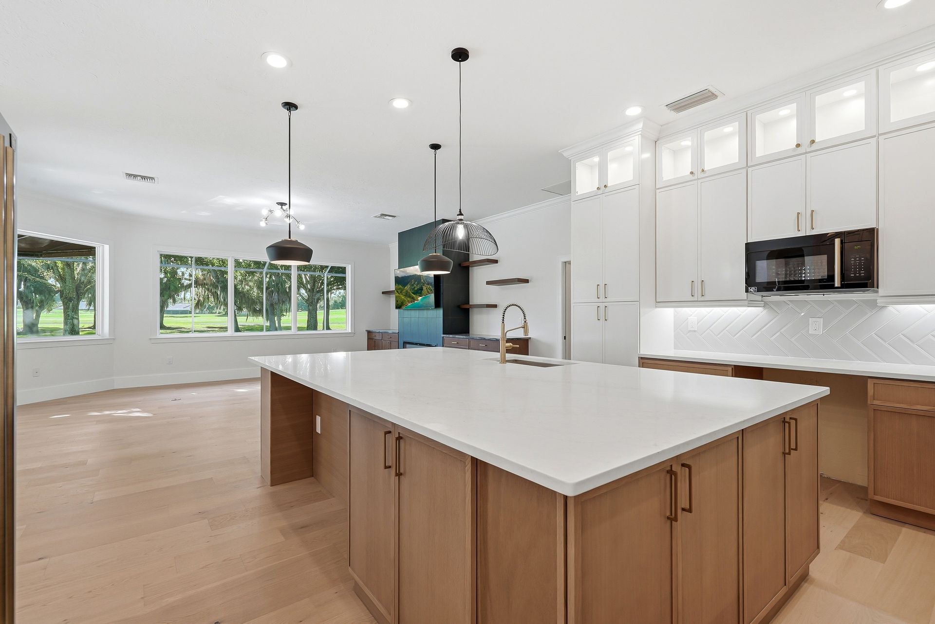 Large kitchen island with light wood-tone cabinetry, white quartz waterfall countertop, and herringbone tile backsplash