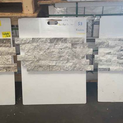 Large white and gray stone-look tile display samples in a showroom rack