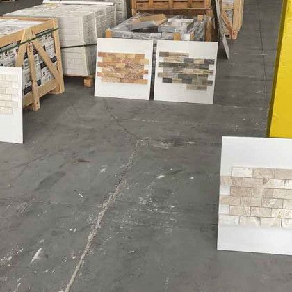 Warehouse aisle with stacked tile sample boards on the floor and pallets in the background