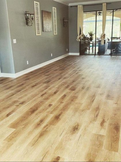 Empty modern living room with gray walls, wood-look floors, and sliding glass doors to a patio