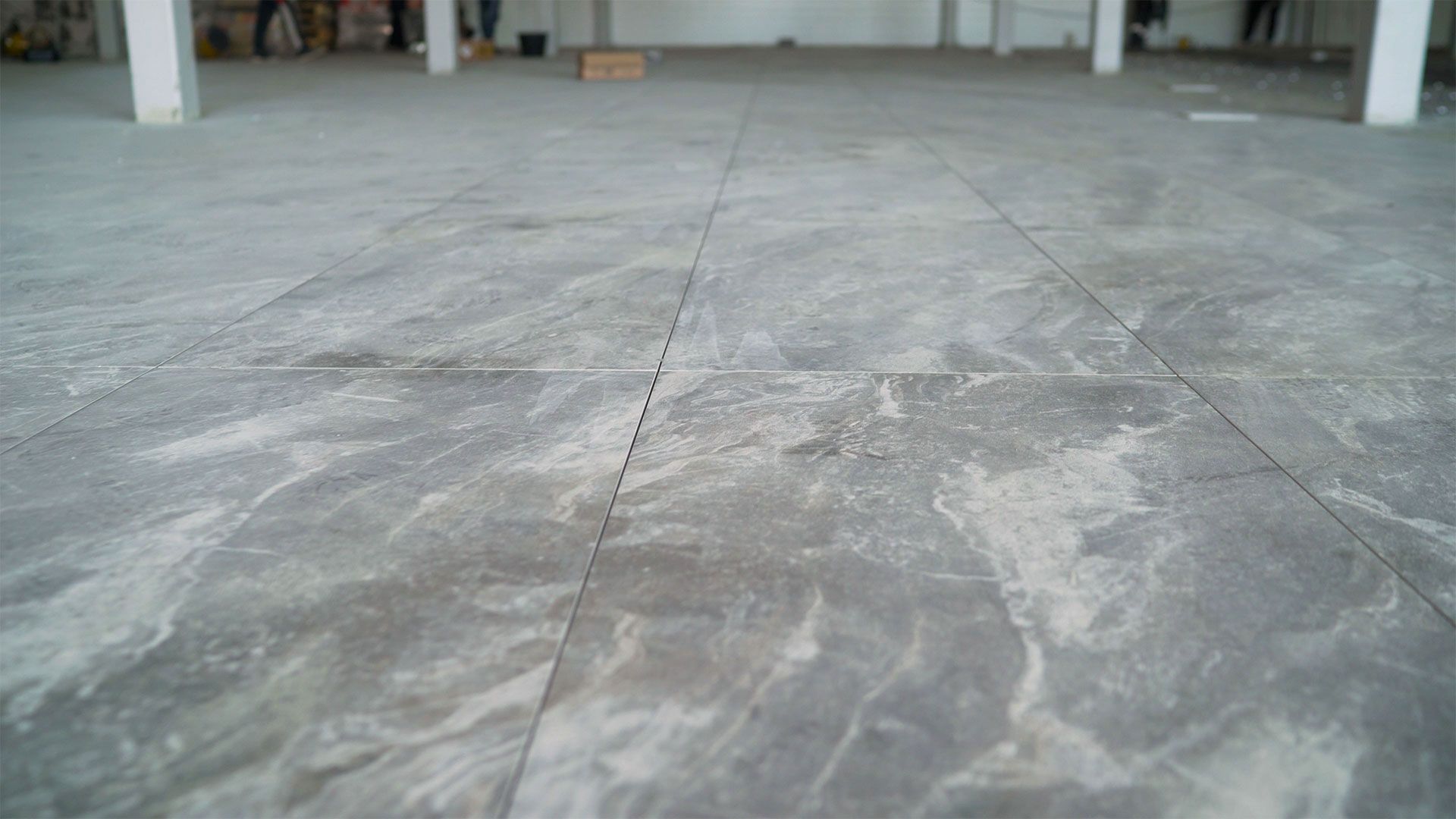 Gray concrete floor with visible cracks and patches in an indoor industrial space