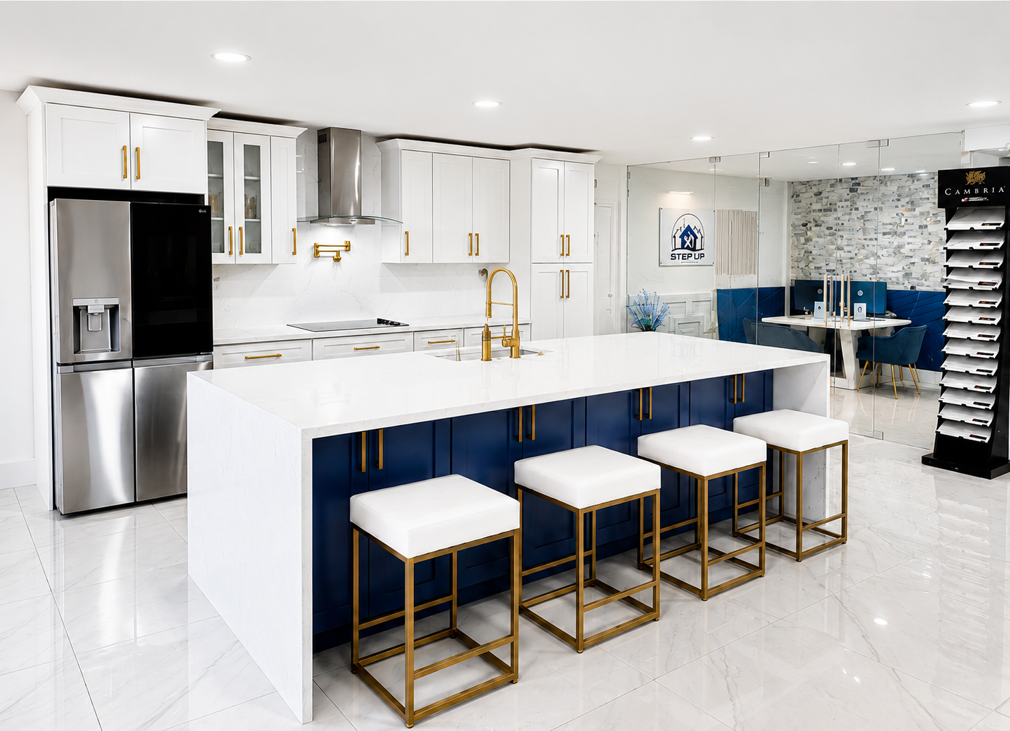 Modern white kitchen with navy island, gold stools, stainless steel fridge, and blue seating area
