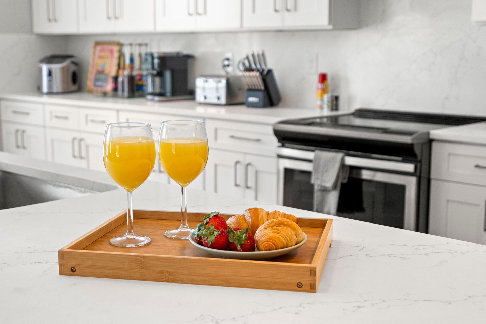 Close-up of a white quartz kitchen island countertop with subtle gray veining, breakfast tray, and white shaker cabinetry in a remodeled kitchen.