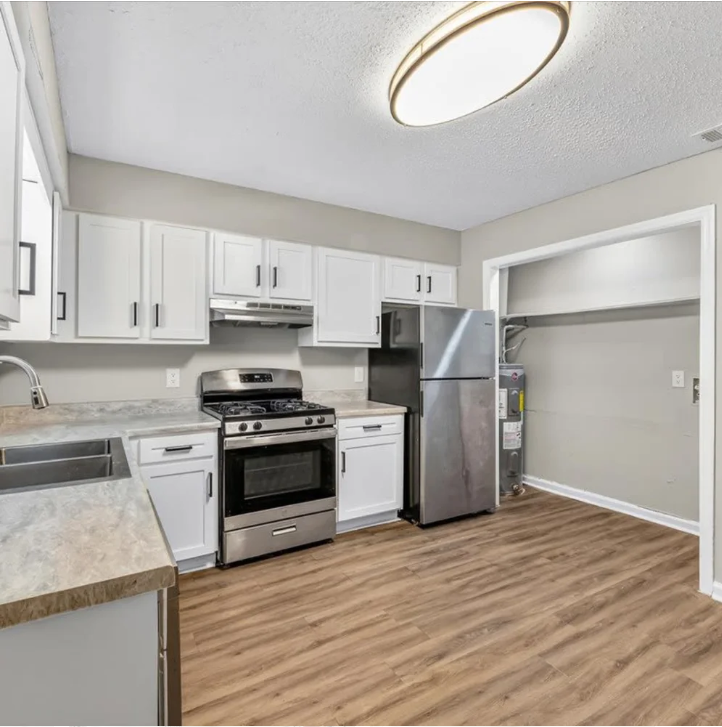 Bright kitchen with white cabinets, stainless steel appliances, and wood-look flooring.