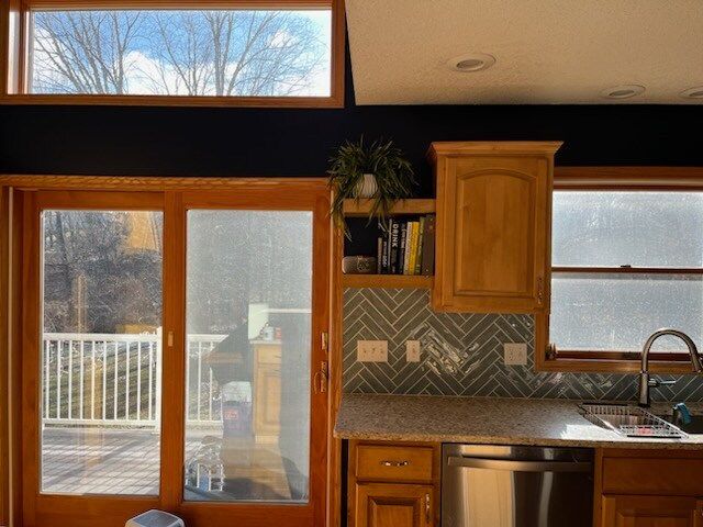 Kitchen with wooden cabinets, a sink, and a deck viewed through sliding glass doors; a small plant sits on a shelf.