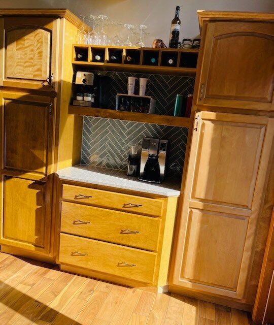 Wooden kitchen cabinets with a built-in coffee station.  Drawers, shelves, and a backsplash are visible.