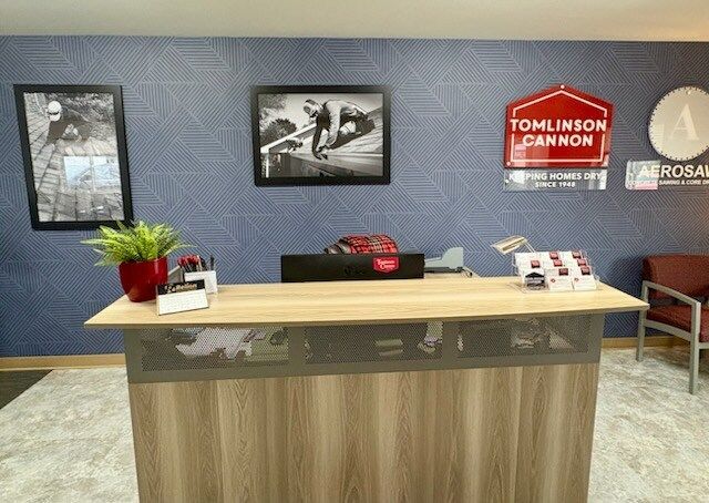 Reception desk with pictures, logos, and a plant on a textured blue wall.