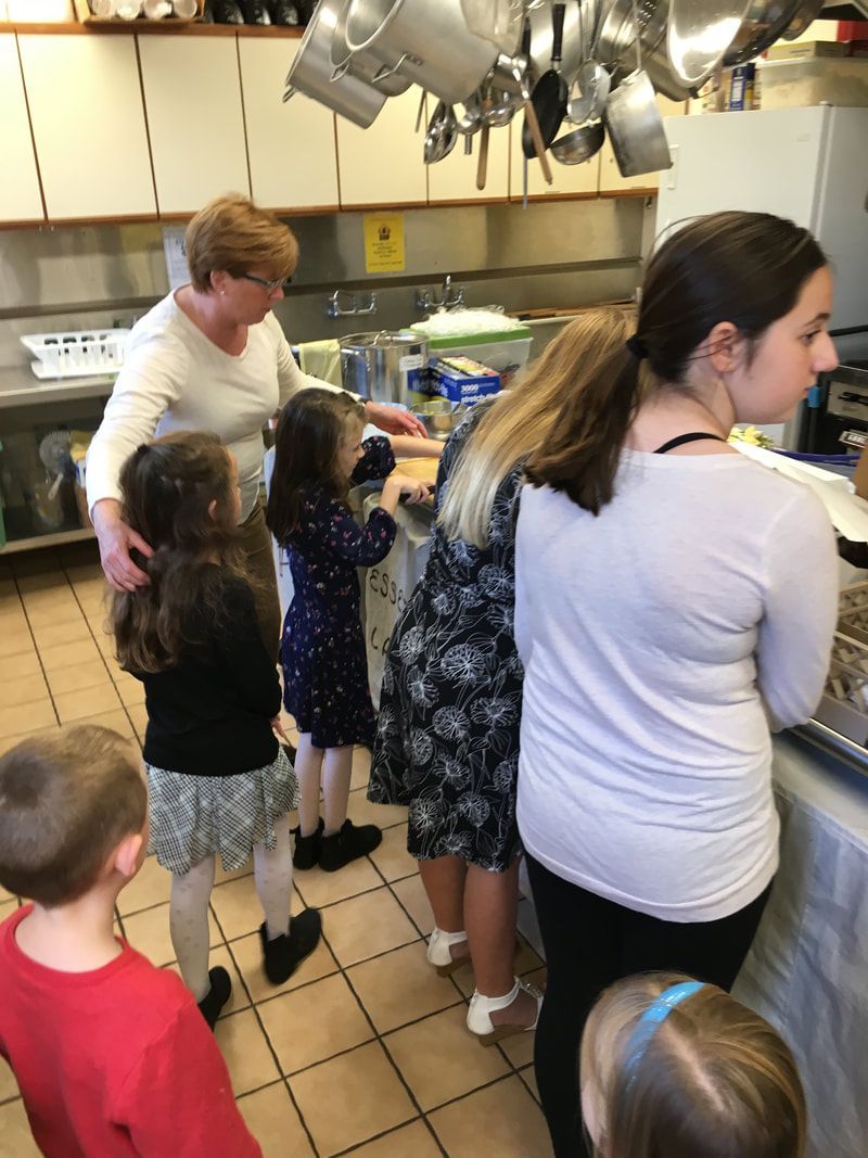 A group of people standing in a kitchen with pots and pans hanging from the ceiling