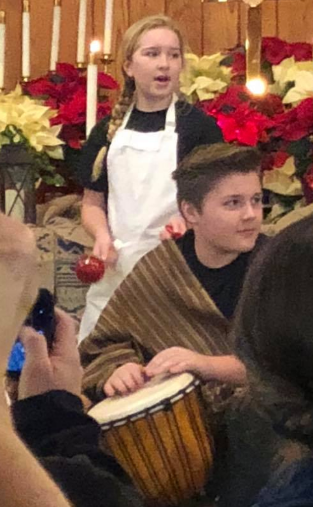A boy and a girl are playing drums in a church.
