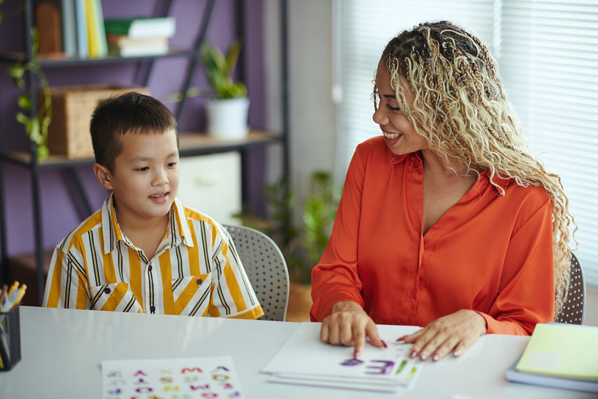A woman is sitting at a table with a young boy.