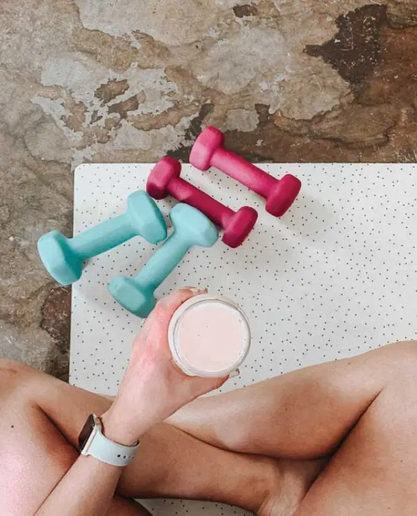 Woman Sitting On Floor With Dumbbells and a Smoothie — Supplements & Organic Produce in Mid North Coast, NSW