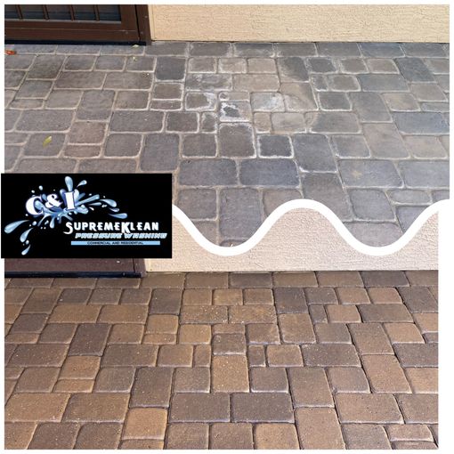 Pressure washer spraying a dark brick patio; boots visible in the foreground, grass in the background.