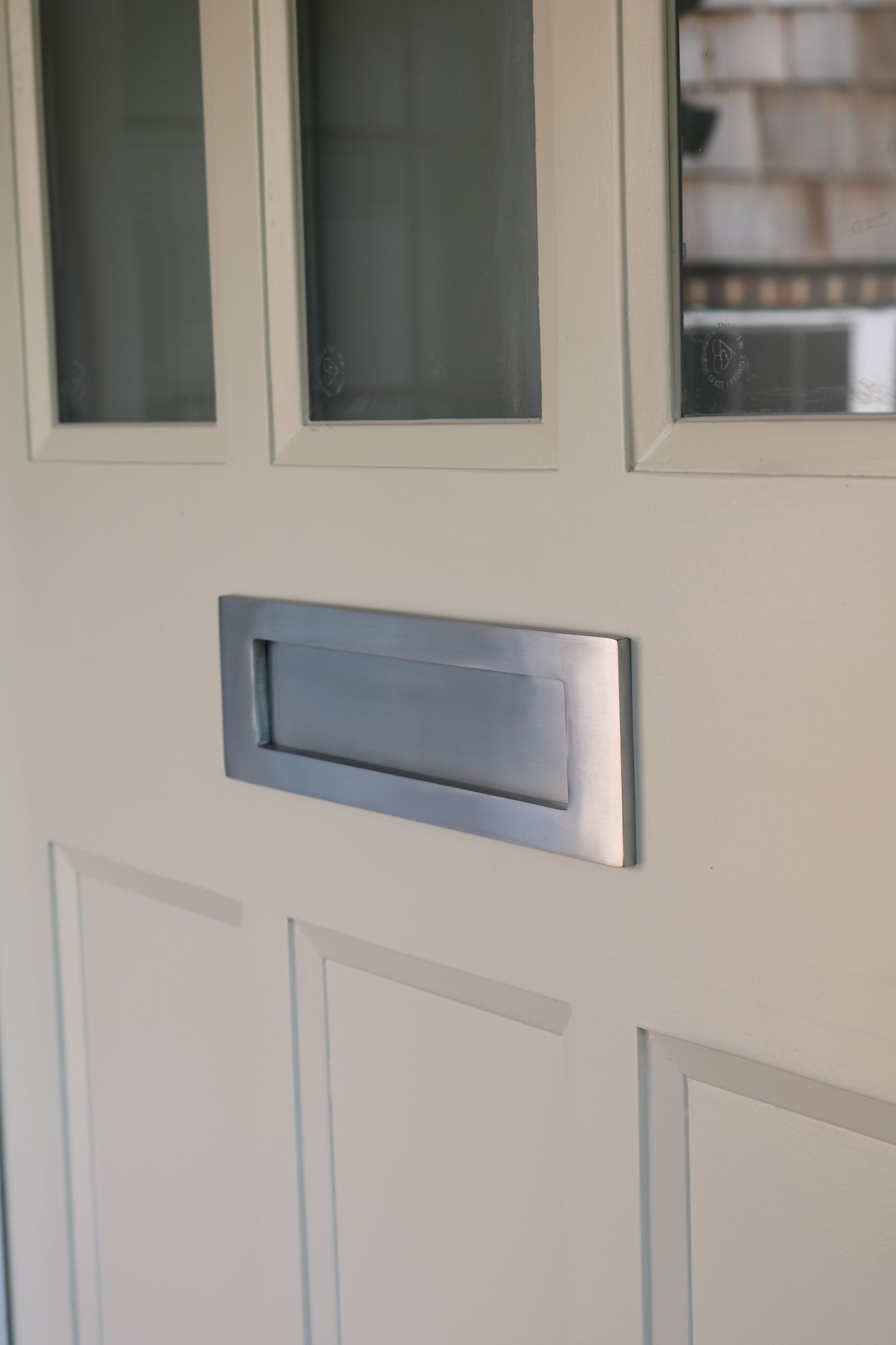 Satin chrome letterbox letterplate on a white door