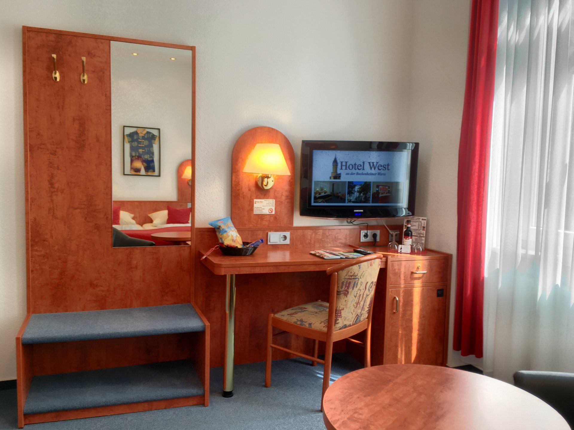 Ein Hotelzimmer mit einem Schreibtisch, einem Stuhl und einem Flachbildfernseher