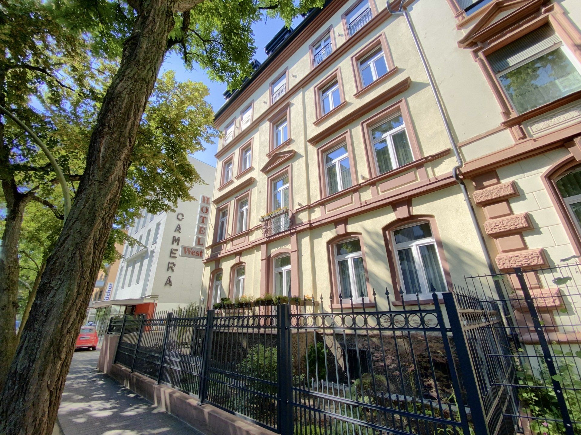 Ein großes Gebäude mit einem Zaun darum und einem Baum davor.