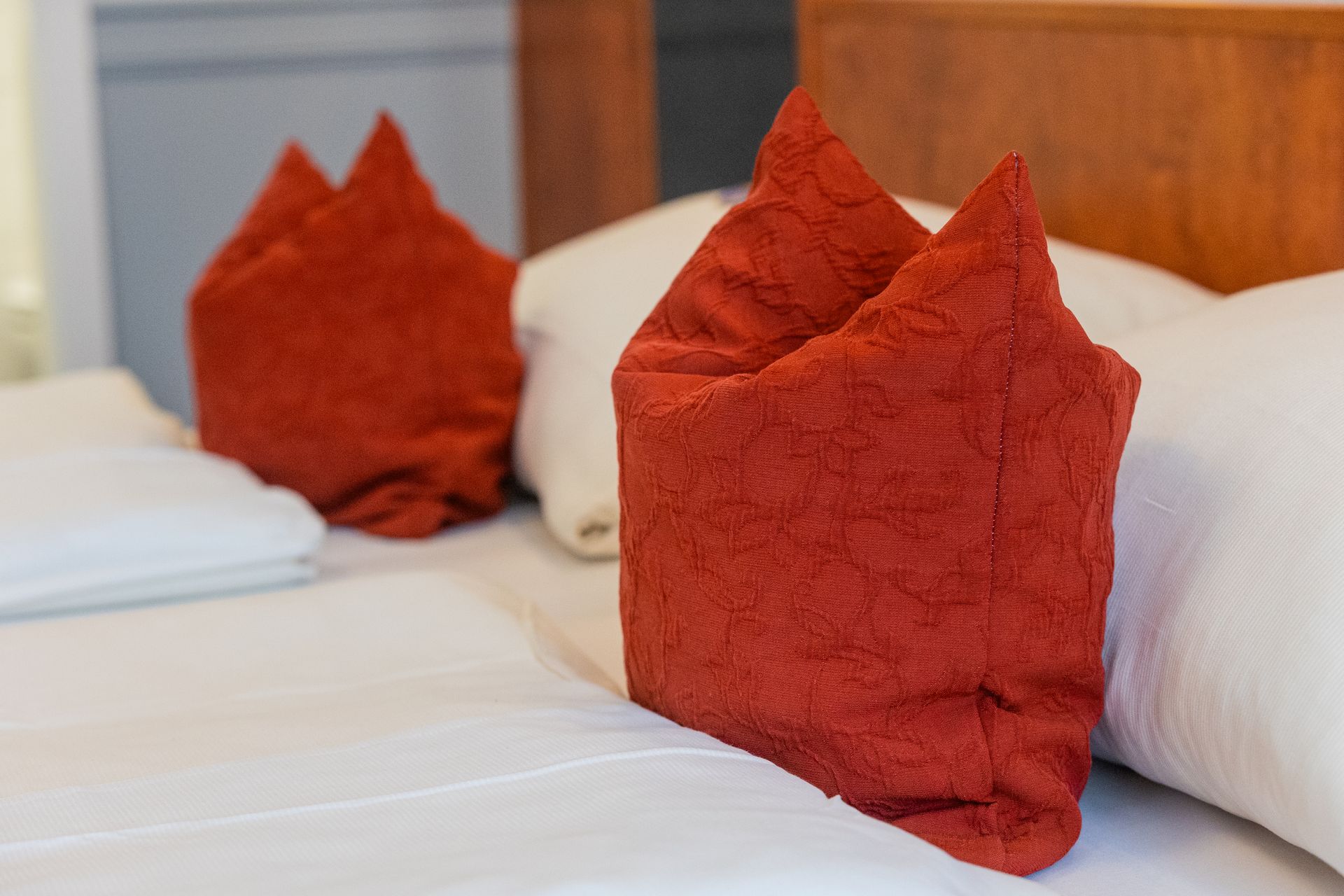 Ein Bett mit zwei Kissen und einem roten Handtuch darauf.