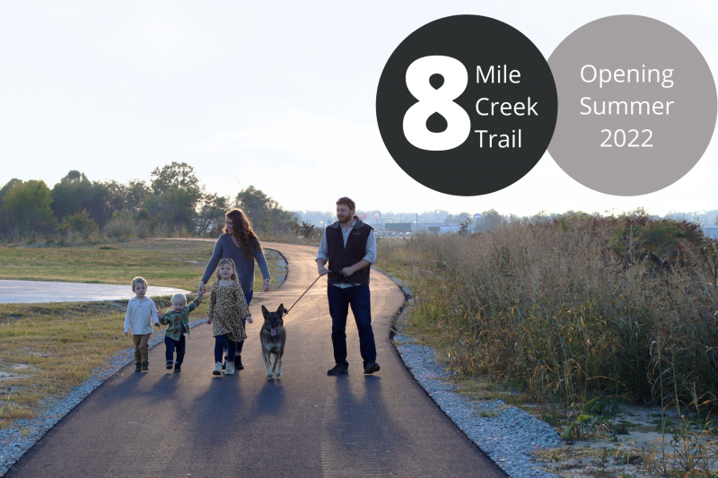 Family walking on a paved trail at sunset, with “8 Mile Creek Trail” and “Opening Summer 2022” text overlay.