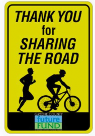 Yellow road sign reading “Thank you for sharing the road” with a runner and cyclist silhouette.