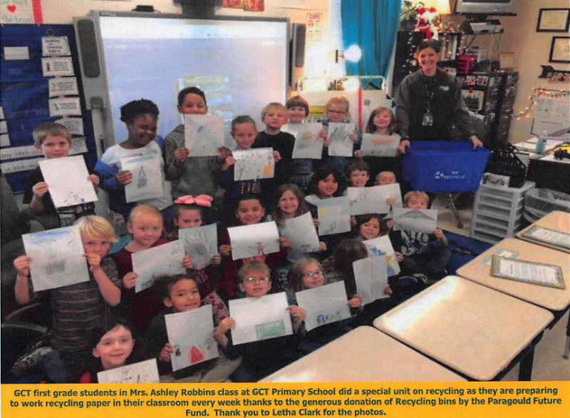 Classroom group holding certificates with a teacher beside a Christmas tree and decorated bulletin board