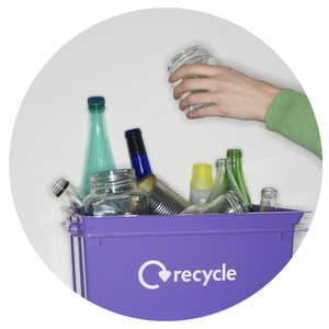 Hands placing a jar into a purple recycle bin filled with glass bottles and cans