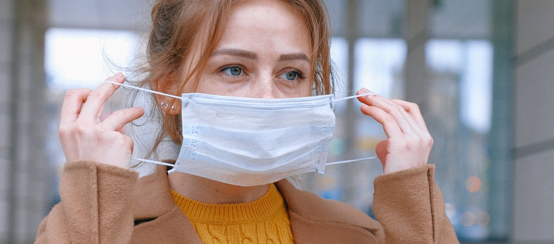 A woman puts on a protective face mask during the Covid-19 pandemic