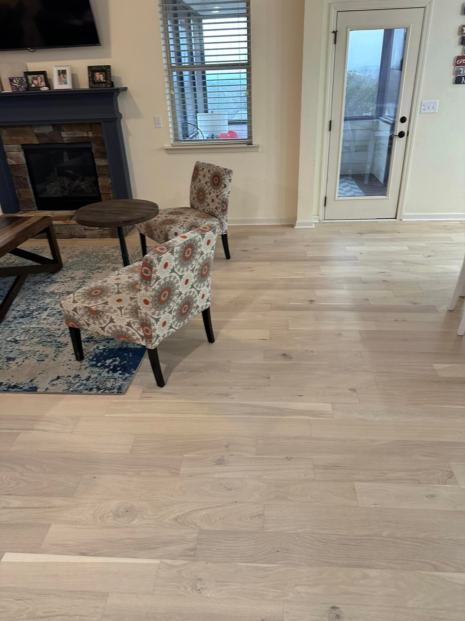 a living room with hardwood floors , chairs and a fireplace .