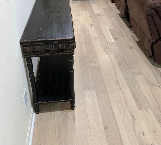 a living room with hardwood floors , a couch , a table and a mirror .