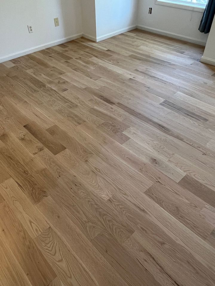 a living room with hardwood floors , a couch , a table and a mirror .