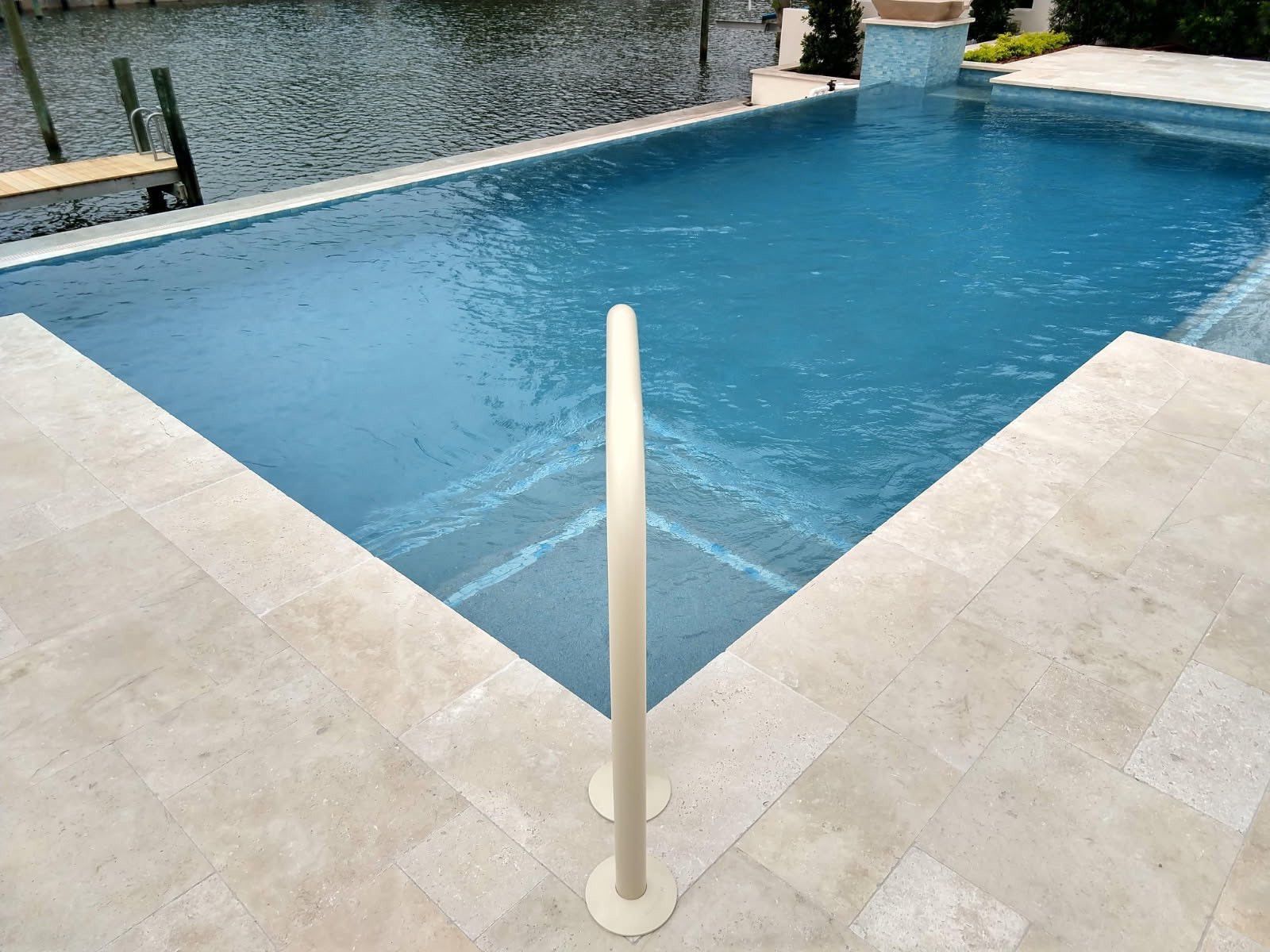 Pool with handrail, blue water, light-colored tile surround.
