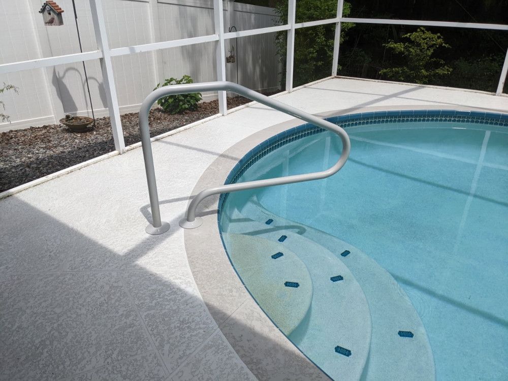 Pool with steps, handrail, surrounded by a white screen enclosure.