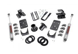 Black metal suspension lift kit components with shocks, brackets, spacers, and hardware laid out on white background