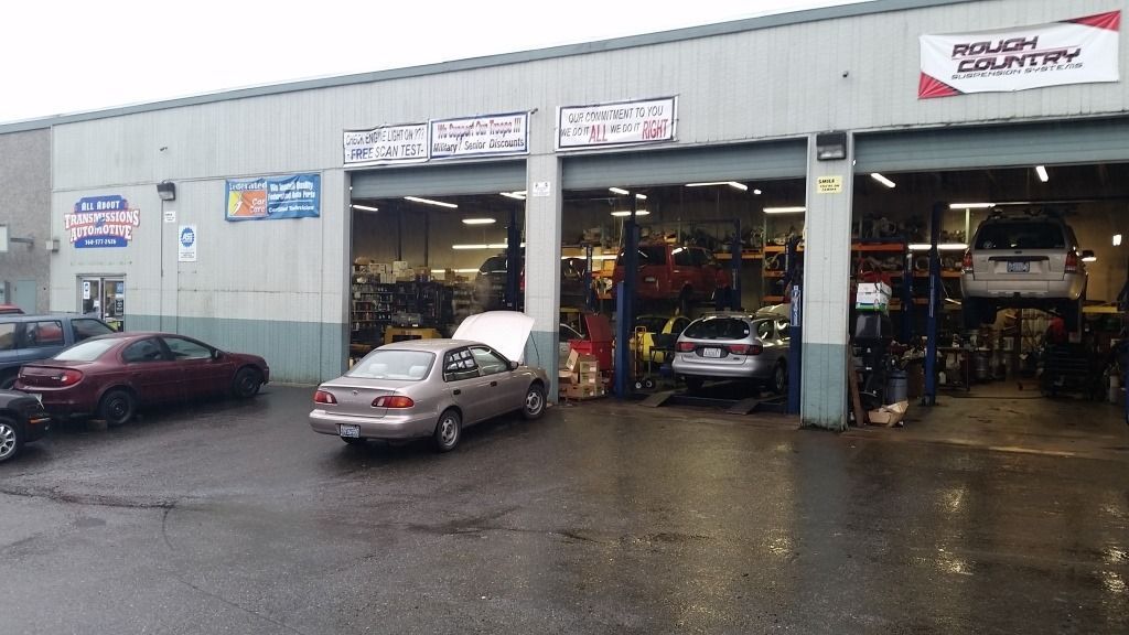 Auto repair shop exterior with cars parked outside on a wet lot
