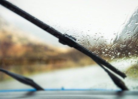 Rainy windshield view from inside a car with wipers clearing the glass
