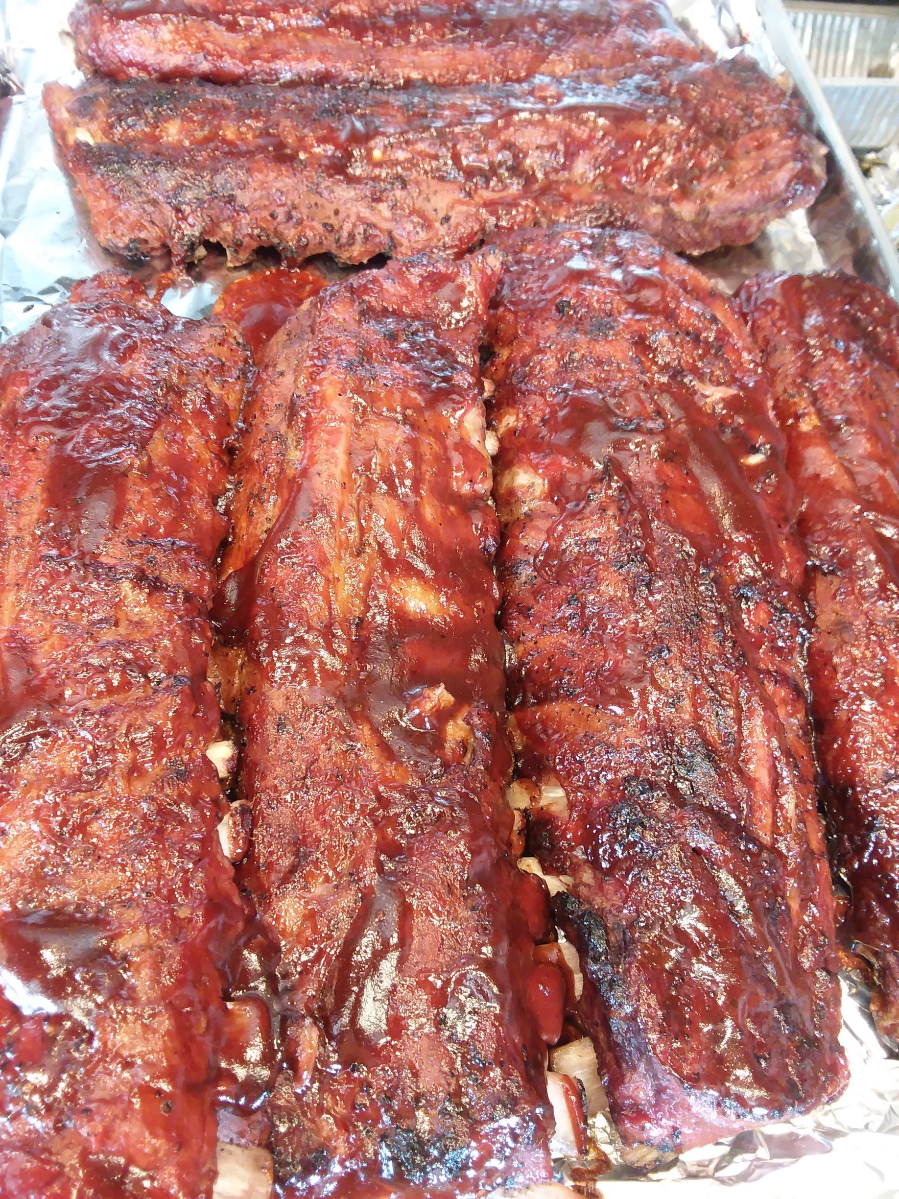 A bunch of ribs are sitting on top of each other on a pan.