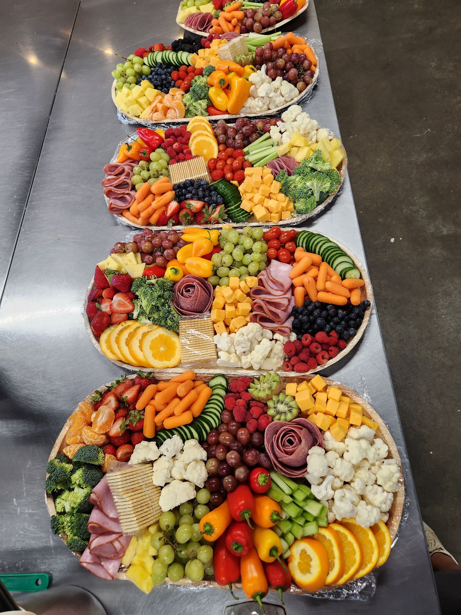 A variety of fruits and vegetables are on plates on a table.
