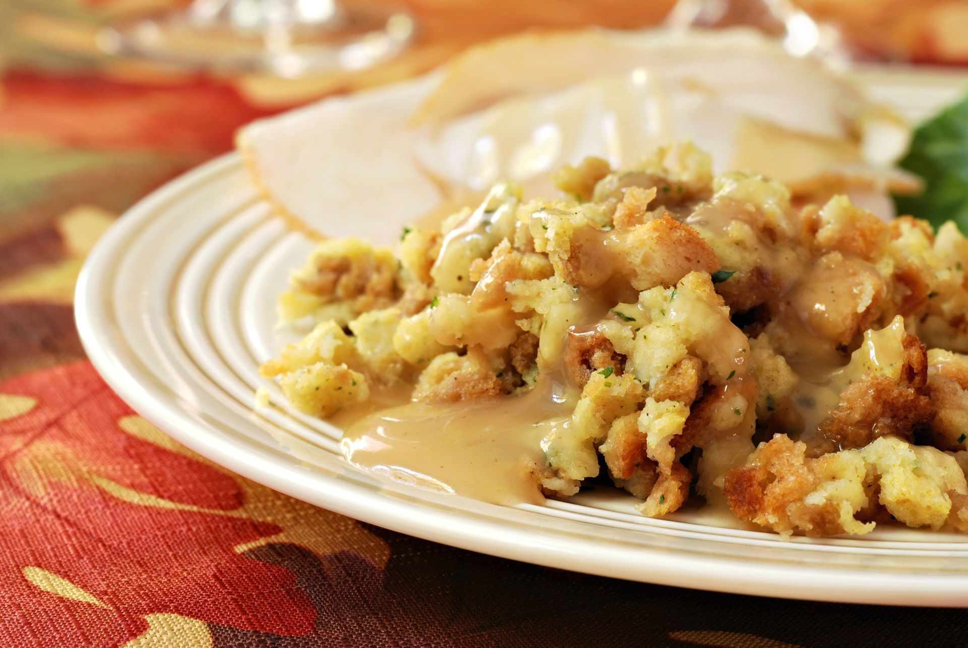 A white plate topped with stuffing and gravy on a table.