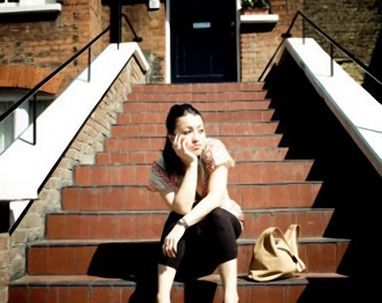 A woman sits on a set of stairs with her hand on her face
