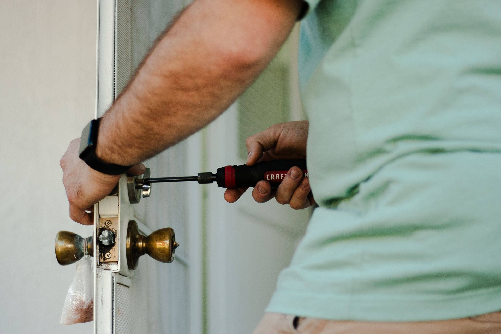 A man is fixing a door with a screwdriver.