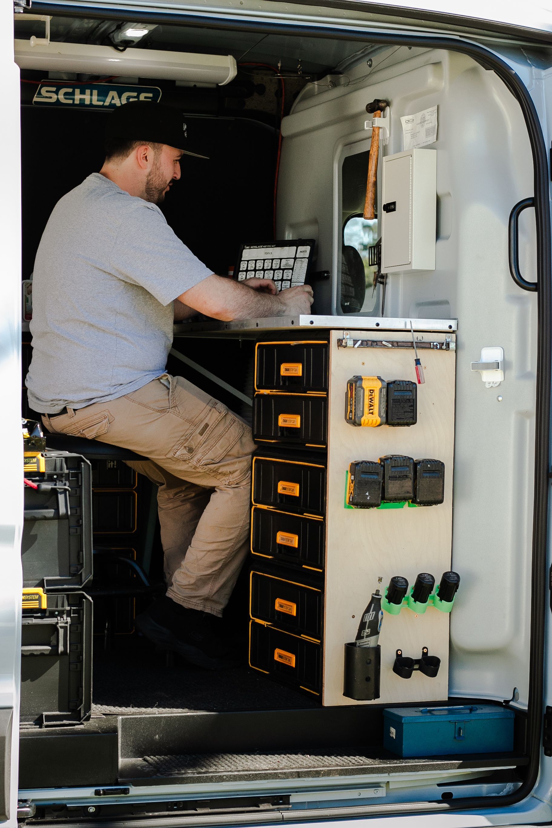 A man is sitting in the back of a van working on a piece of equipment.