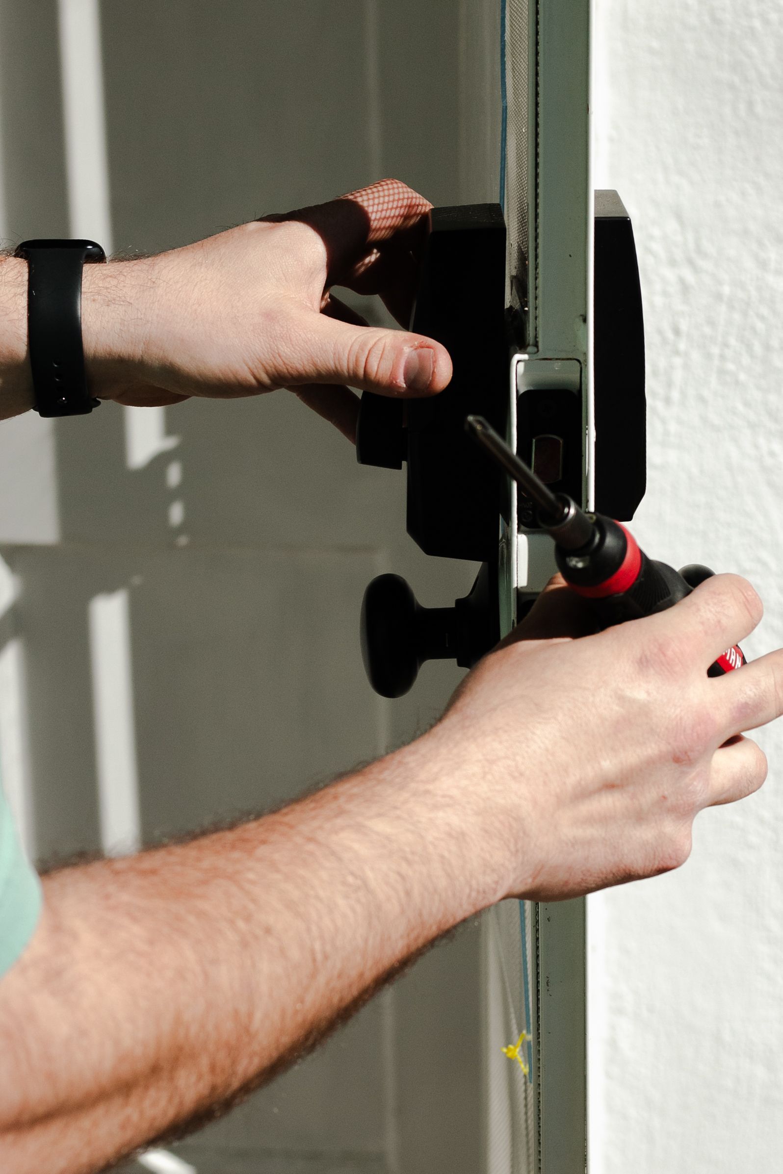 A man is fixing a door with a screwdriver.