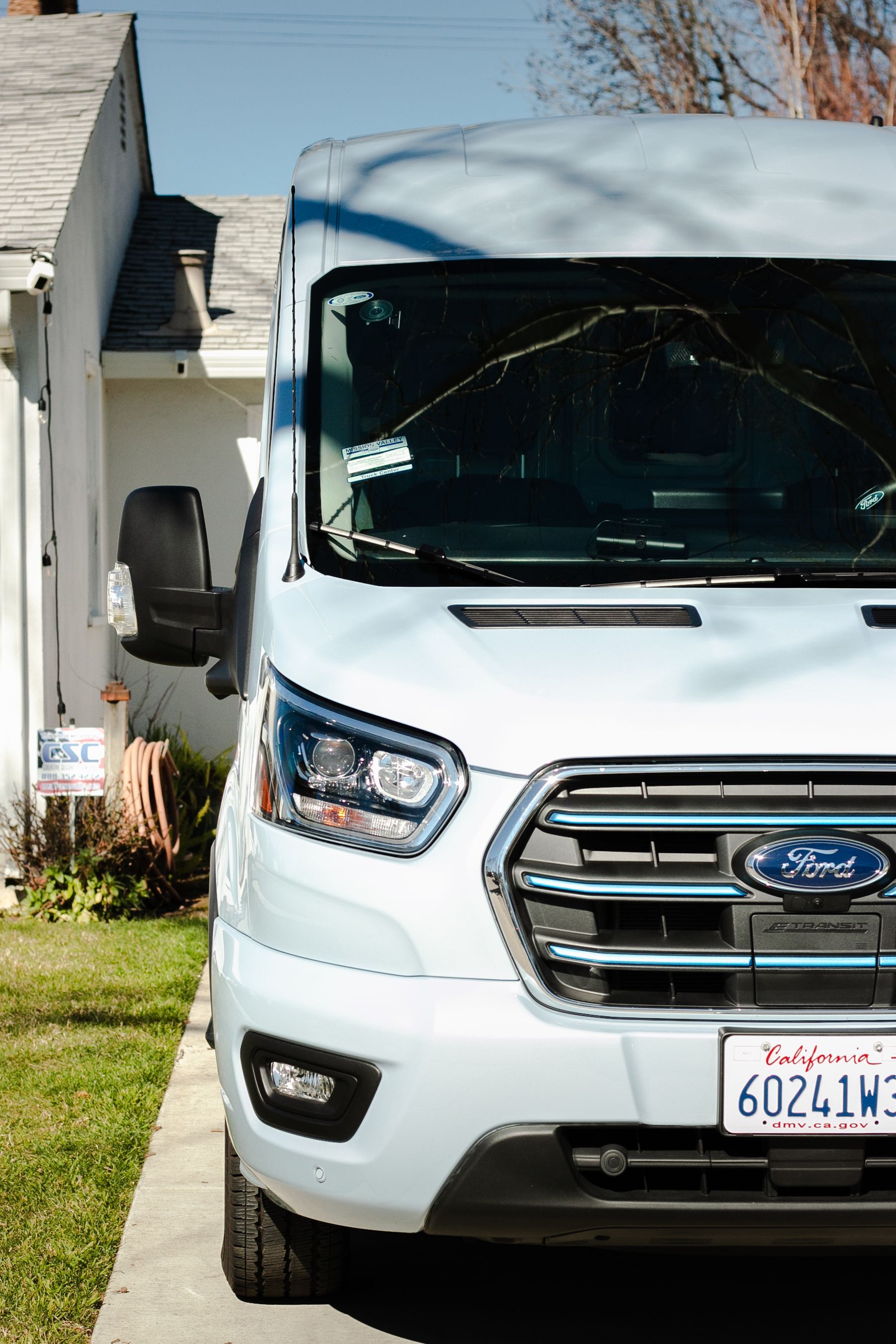 A white ford van is parked in front of a house.