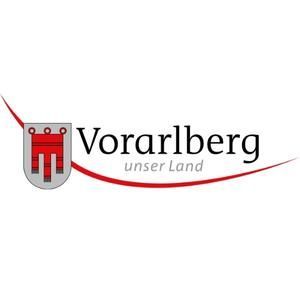 Ein Logo für Vorarlberg Unser Land mit einem Wappen auf weißem Hintergrund.