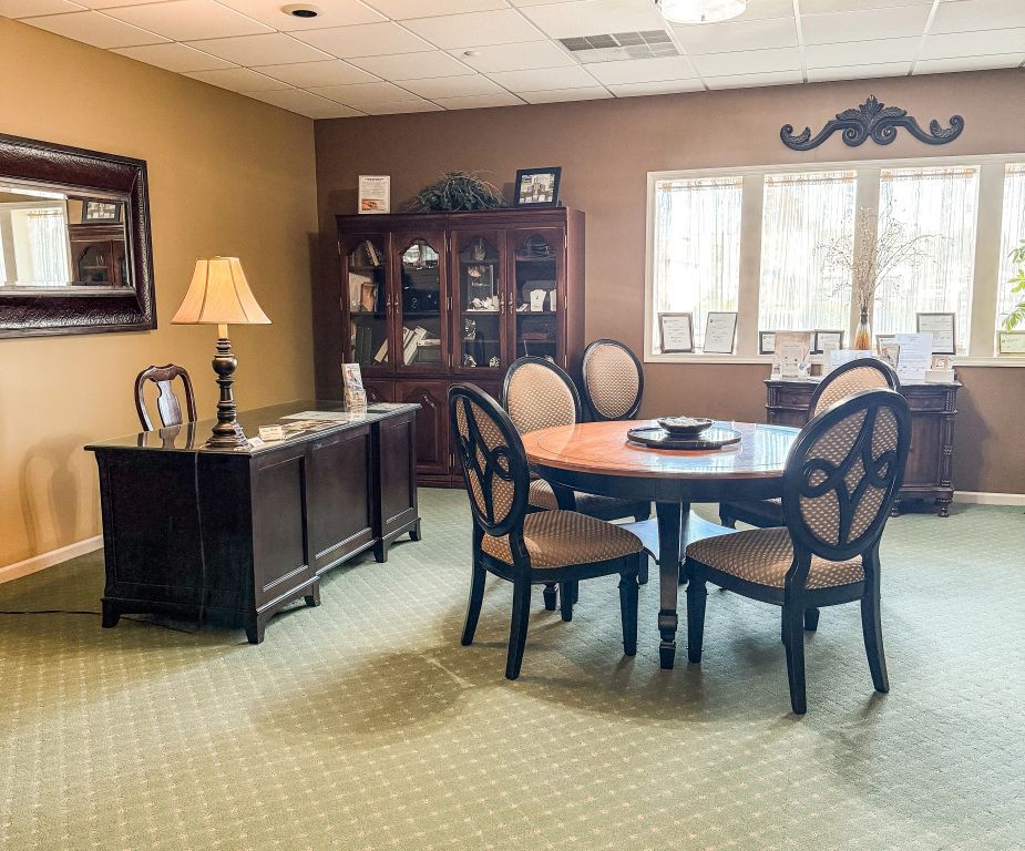 A well-lit office with a table and chairs, cabinet, and desk, featuring beige and brown tones.
