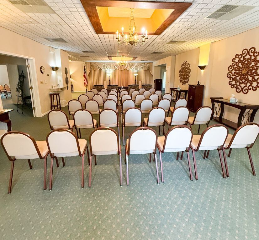 Rows of chairs face a draped podium in a light-filled meeting room.