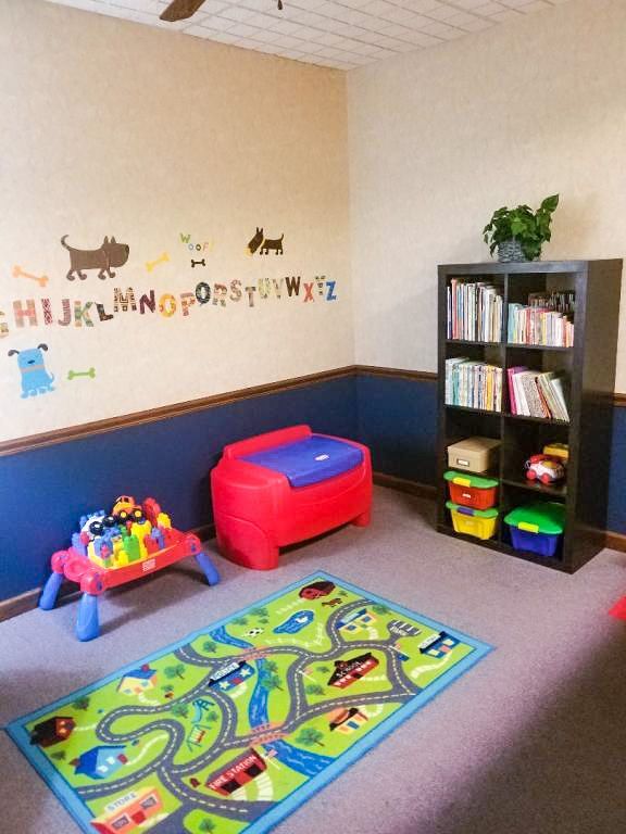 Playroom with a road map rug, toys, storage, and alphabet wall art.