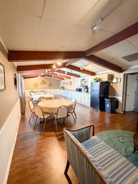 Interior of a community center with tables and chairs set up, kitchen, and seating area.