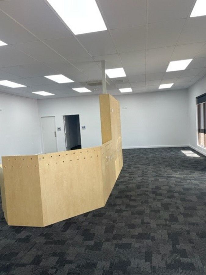 A large empty room with a wooden counter and a black carpet.