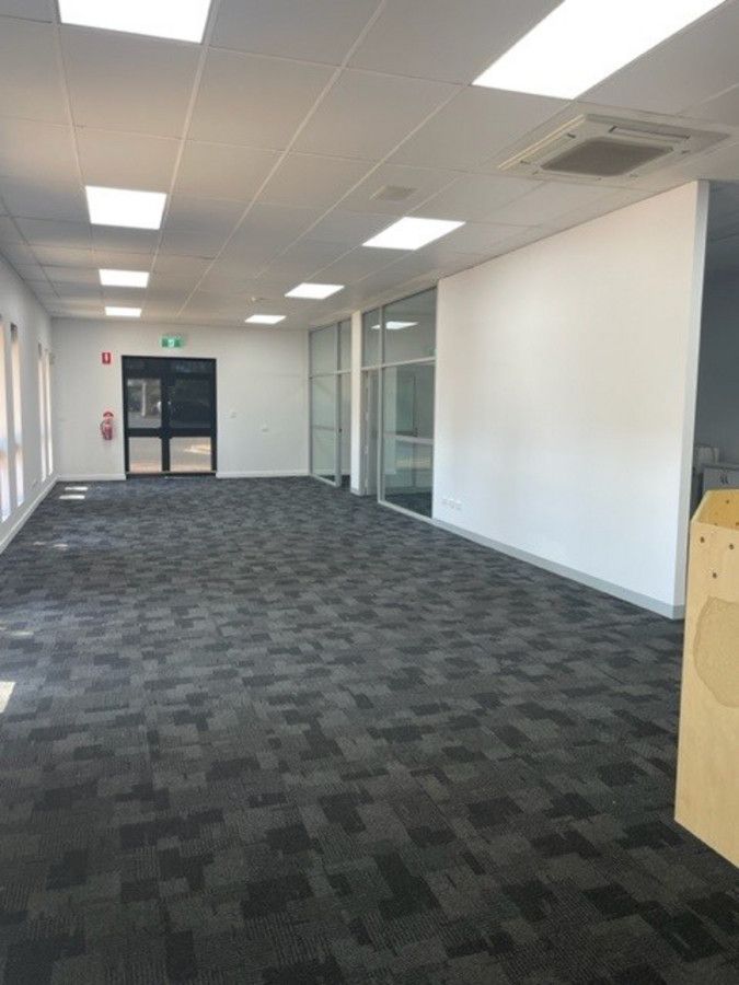 A large empty room with a black carpet and white walls.