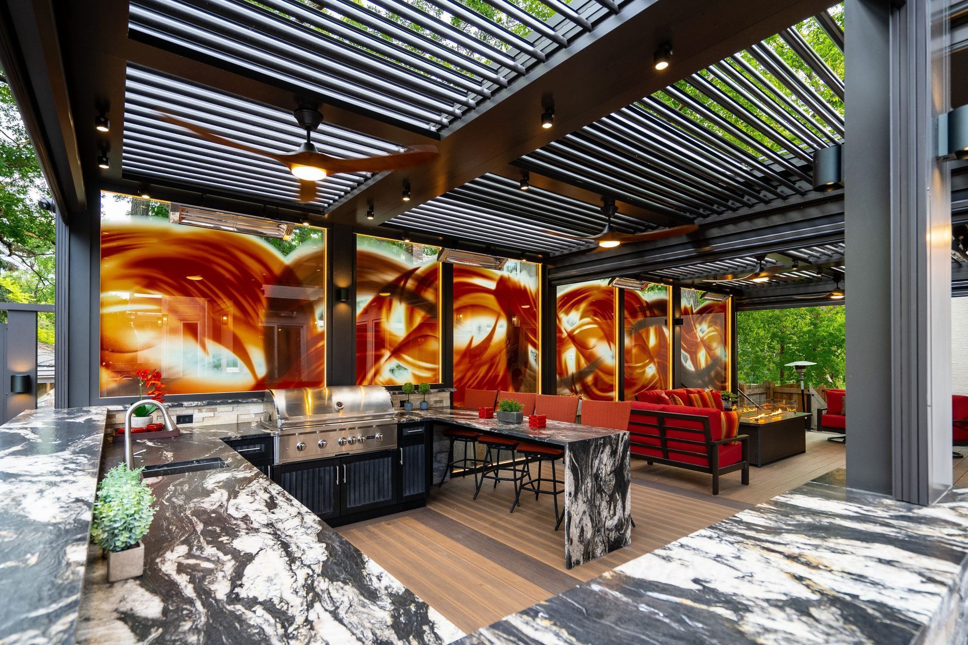 Outdoor kitchen with grill, seating, and abstract art under a pergola.