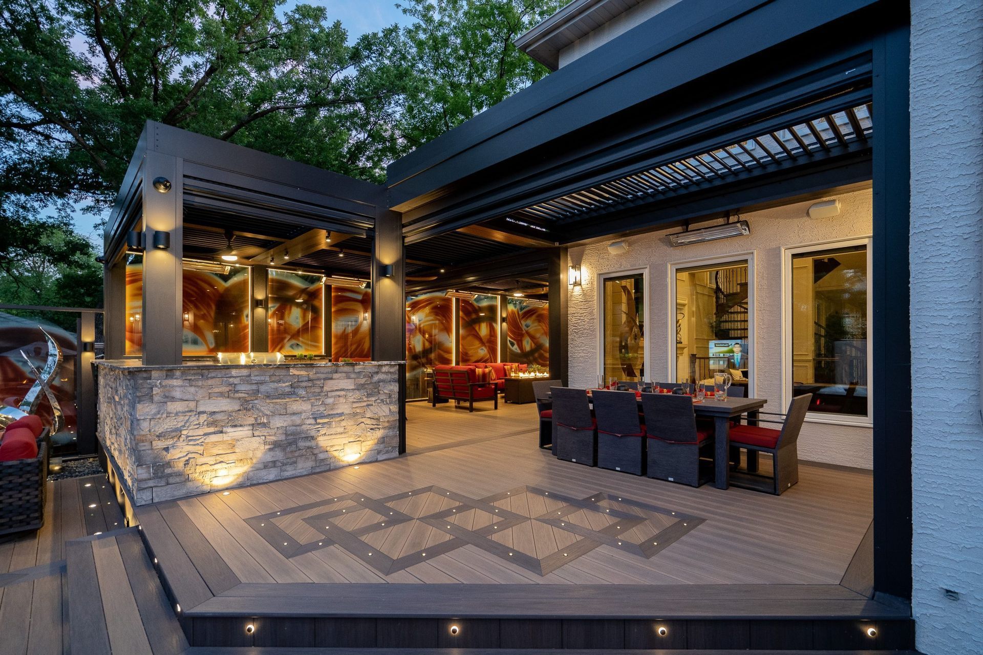 Outdoor patio with pergola, stone bar, and dining area. Decking has decorative inlay, with built-in lighting.